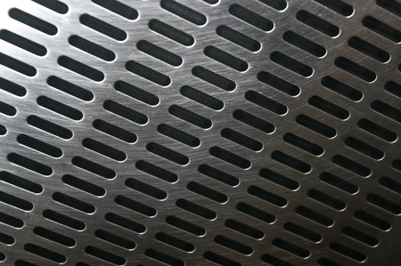 stainless steel grating with oblong holes on black background, close-upの写真素材