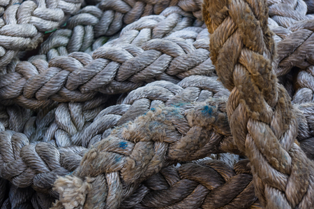 Old braided rope on the wooden deck of a sea boat, cleats, anchor mechanismsの写真素材