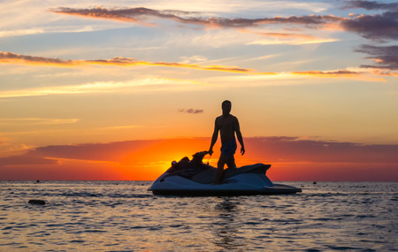 silhouette of a man on a jet ski in the sun on the sea sunset in summer eveningの写真素材
