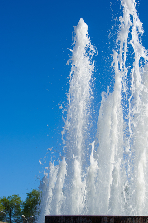 Fountain in city park on hot summer day, beautiful bright streams of sparkling water, drops and splashes.の写真素材