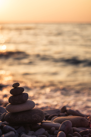 folded pyramid Zen pebble stones on the sea beach at sunsetの写真素材
