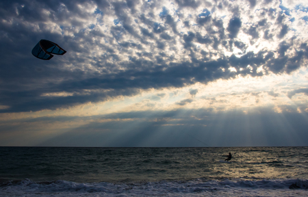 kitesurfer rides a kite-surf on waves of the sea in a small storm on a summer dayの写真素材