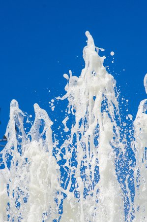 Fountain in city park on hot summer day, beautiful bright streams of sparkling water, drops and splashes.の写真素材