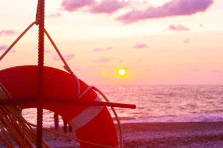 orange lifebuoy on a pebbly sea beach, sunsetの写真素材