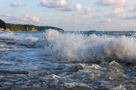 sea landscape is a pebbly beach with waves in white foam, a beautiful sky with clouds, a warm summer dayの写真素材