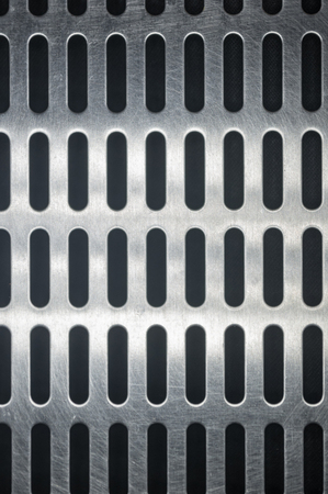 stainless steel grating with oblong holes on black background, close-up