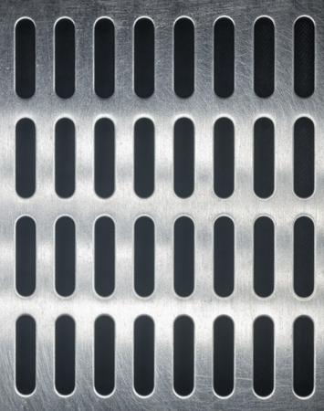 stainless steel grating with oblong holes on black background, close-up