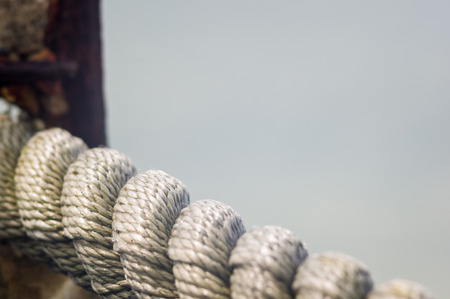 old worn battered marine rope on the pebble beach on a Sunny summer day, top viewの写真素材