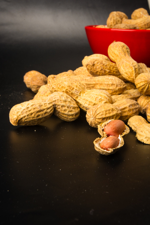 Peanuts, Arachis hypogaea, in shell on dark background, close up, selective focus