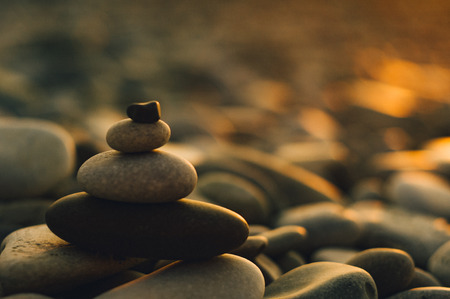 folded pyramid Zen pebble stones on the sea beach at sunsetの写真素材