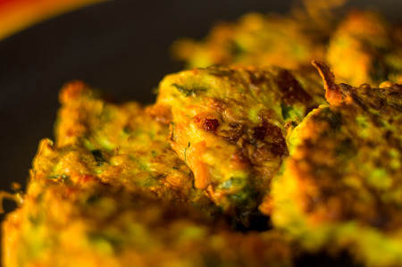 Fried vegetable fritters with zucchini, carrots, herbs, eggs, seasonings and cheese, close-up, selective focusの写真素材