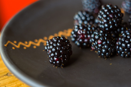 large juicy fresh blackberry berries on a ceramic plate, close-up