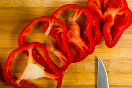 sliced fresh red paprika, bell pepper on bamboo cutting board, close up