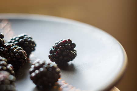 large juicy fresh blackberry berries on a ceramic plate, close-upの写真素材