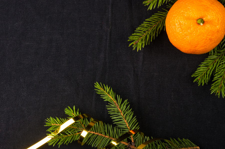 New Year Concept. Christmas decorations from fir-tree branches and the fruits of mandarin orange on black backgroundの写真素材