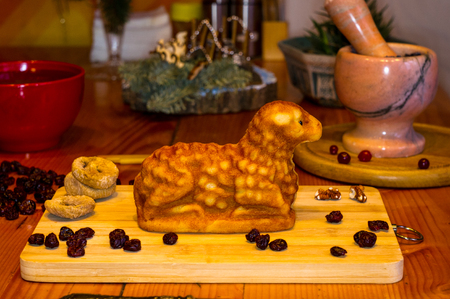 preparation of treats for traditional Orthodox Christmas - handmade baked cookies in the form of lambkin, dried fruits, cranberries, honey, nuts, rice pudding, mortar with poppy seeds, Church candles on a wooden tableの写真素材