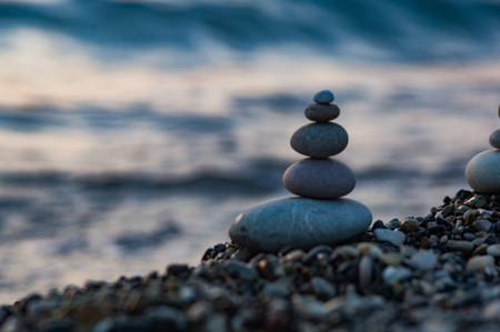 folded pyramid Zen pebble stones on the sea beach at sunsetの写真素材