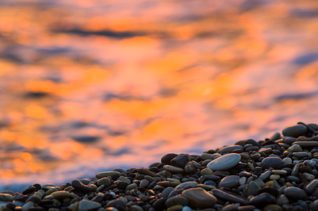 pebble stones on the sea beach, the rolling waves of the sea with foamの写真素材