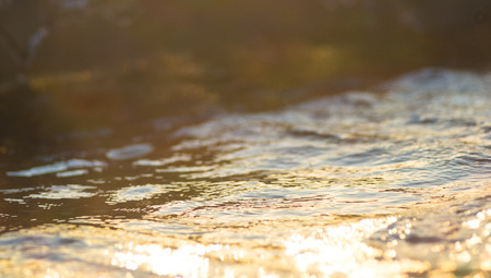 pebble stones on the sea beach on a warm summer day, the rolling waves of the blue sea with white foamの写真素材
