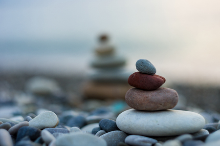 folded pyramid Zen pebble stones on the sea beach at sunsetの写真素材