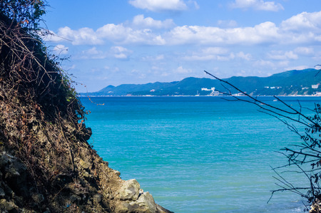 rocky sea shore with pebble beach, transparent waves with foam, on a warm summer dayの写真素材
