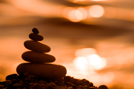 folded pyramid Zen pebble stones on the sea beach at sunsetの写真素材