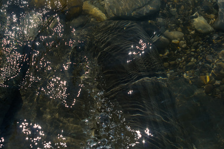 pebble stones on the sea beach on a warm summer day, the rolling waves of the blue sea with white...