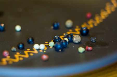 juniper berries and allspice in a ceramic plate on a wooden table, close-up