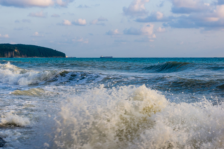 sea landscape is a pebbly beach with waves in white foam, a beautiful sky with clouds, a warm summer dayの写真素材