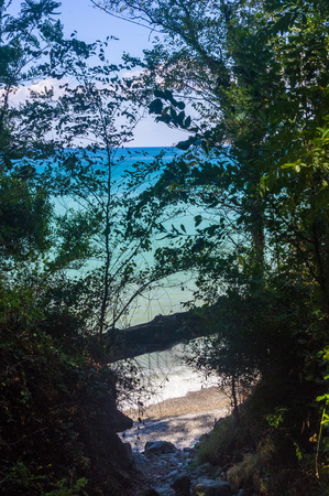 rocky sea shore with pebble beach, transparent waves with foam, on a warm summer dayの写真素材