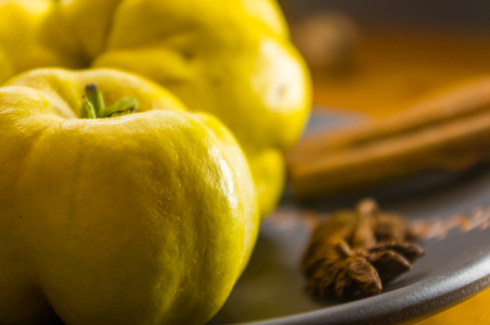still life - large yellow quince fruits on a ceramic plate, with anise, cinnamon, and walnutsの写真素材