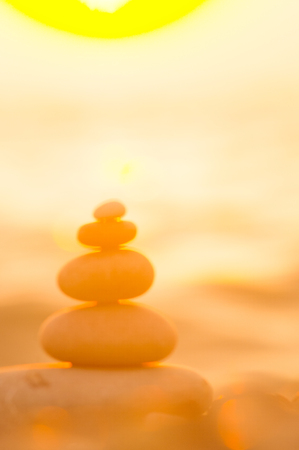 folded pyramid Zen pebble stones on the sea beach at sunsetの写真素材