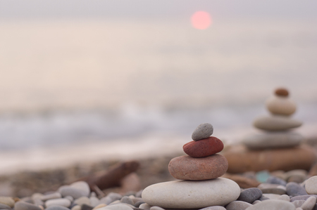 folded pyramid Zen pebble stones on the sea beach at sunsetの写真素材