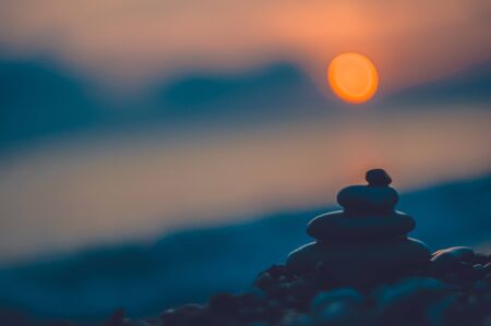 folded pyramid Zen pebble stones on the sea beach at sunsetの写真素材