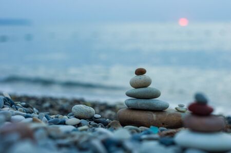 folded pyramid Zen pebble stones on the sea beach at sunsetの写真素材