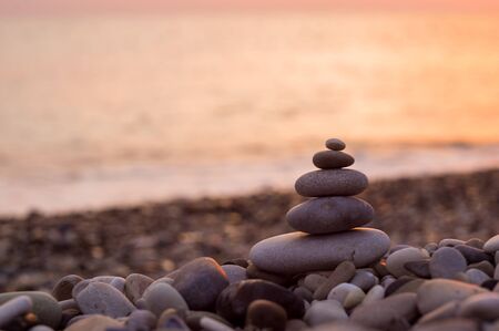 folded pyramid Zen pebble stones on the sea beach at sunsetの写真素材