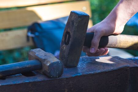 Blacksmith performs the forging of hot glowing metal on the anvil.の写真素材