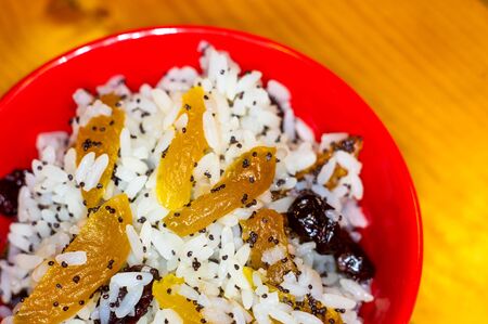 handmade preparation of treats for traditional Orthodox Christmas - rice pudding with fruits, cranberries, honey, nuts, Church candles on a wooden tableの写真素材