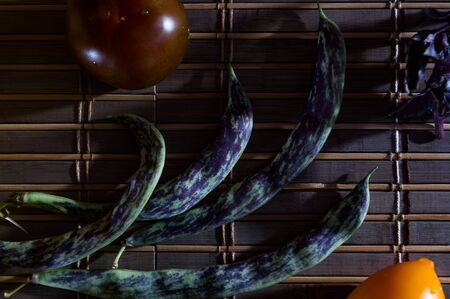 Still life - asparagus beans, purple Basil, yellow and chocolate tomatoes on bamboo Mat