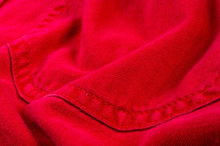 clothing items washed red cotton fabric texture with seams, clasps, buttons and rivets, macro, close-upの写真素材