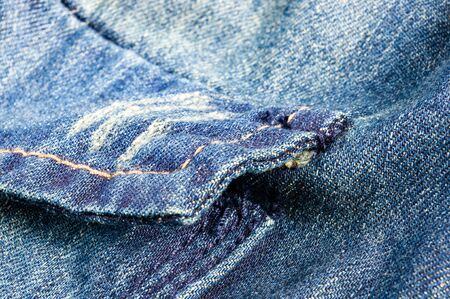 clothing items blue washed faded jeans cotton fabric texture with seams, clasps, buttons and rivets,...