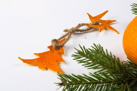 New Year Concept. Christmas decorations from tangerine peel, fir-tree branches and the fruits of mandarin orange on white backgroundの写真素材