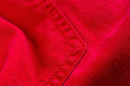 clothing items washed red cotton fabric texture with seams, clasps, buttons and rivets, macro, close-upの写真素材