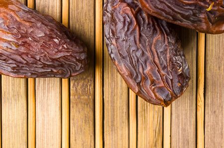 Big luxury dried date fruit in bowls on the bamboo mat, kurma ramadan kareem concept.