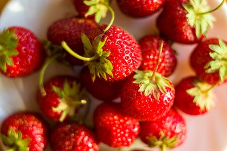 fresh ripe berries strawberries on white ceramic plate, macroの写真素材