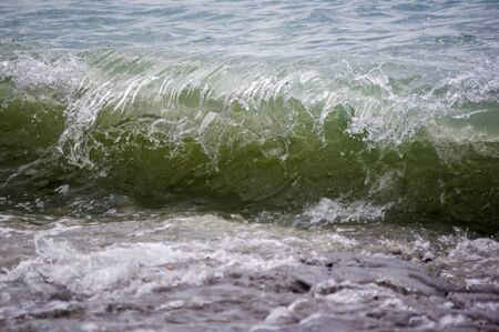 sea landscape is a pebbly beach with waves in white foam, a beautiful sky with clouds, a warm summer dayの写真素材
