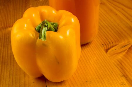 fresh yellow paprika, bell pepper and a bottle of pumpkin juice, close upの写真素材