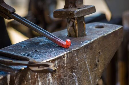 blacksmith performs the forging of hot glowing horseshoe on the anvil, close-upの写真素材