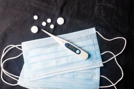 Background for news about the novel coronavirus COVID-19 - protective medical masks and thermometer.の写真素材