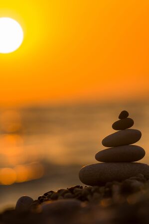 folded pyramid Zen pebble stones on the sea beach at sunsetの写真素材